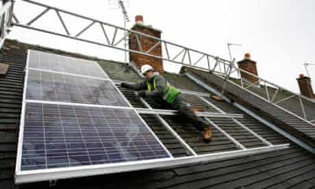 A worker fits solar panels to a roof of a council house in Wrexham , Wales