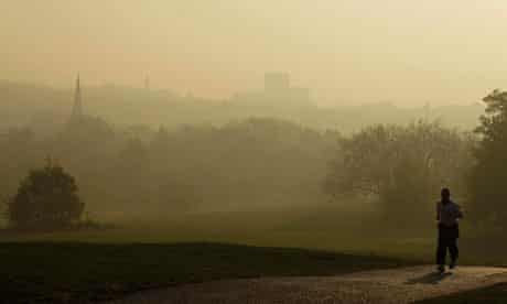 Air pollution in London : A man jogs on Parliament Hill on Hampstead Heath with smog in the distance