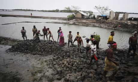 Bangladeshi villagers repair a vital flood-protecting embankment