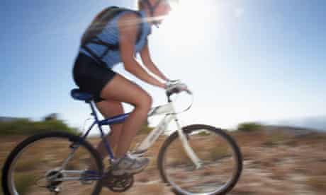 Bike blog : Woman mountain biker cycling across extreme terrain in bright sunlight