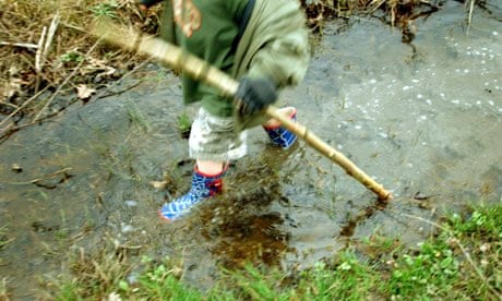 Few UK children connected to nature : Child playing in a stream in a forest in Autumn