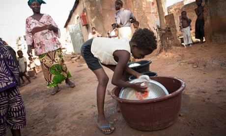 MDG : Slavery : A child (slave) washes dishes in a crowded a slum in Bamako, Mali