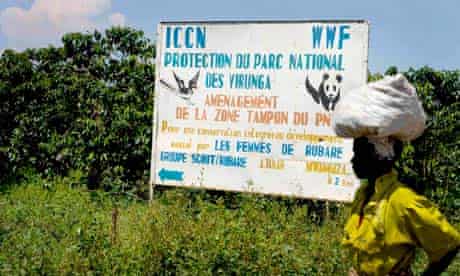 Local woman passing a sign for Virunga National Park, DRC