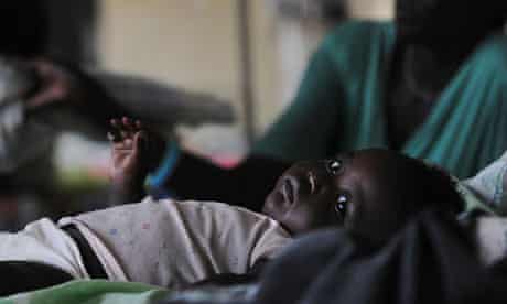 A malaria-infected baby lays in a bed in