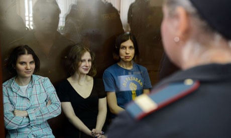 Members of Pussy Riot sit in a glass cage during their trial in Moscow