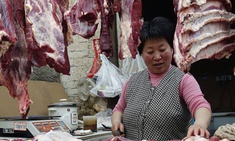 A butcher processes meat at a shop in Beijing