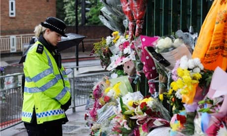 A policewoman in Woolwich looks at flowers left by members of the public where Lee Rigby was killed