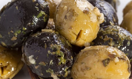 Green and black olives on wooden spoon