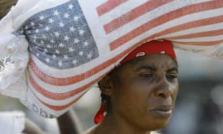 A Haitian woman carries a bag of rice donated by USAid