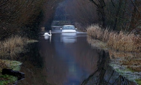 Flooded road on on the Somerset Levels : A car drives through flood water 