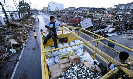 MDG : Policemen secure a truck load of relief goods in Tacloban after typhoon Haiyan, Philippines