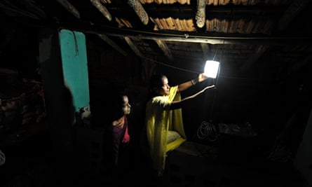 Villagers switches on a light powered by solar energy in the village of Morabandar, India