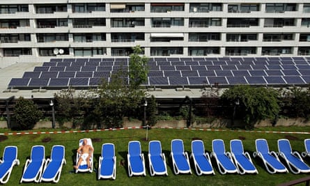 Solar energy in Germany : A man sunbathes at a rooftop spa next to solar cell panels in Berlin