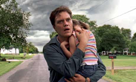 Take Shelter: distressed man carries young daughter as stormclouds mass behind them