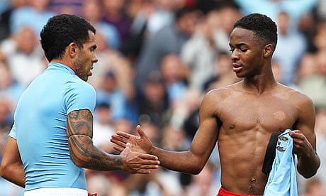 Raheem Sterling of Liverpool with Manchester City's Carlos Tevez