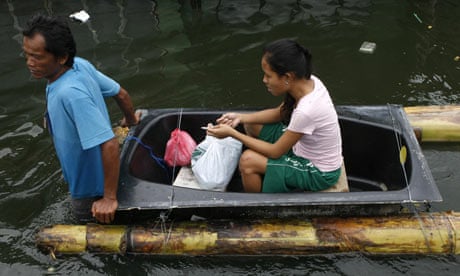 A woman sitting on an improvised raft is pulled through the floodwaters in San Pedro, Philippines
