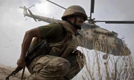 Pakistani soldier crouches a helicopter takes off in South Waziristan