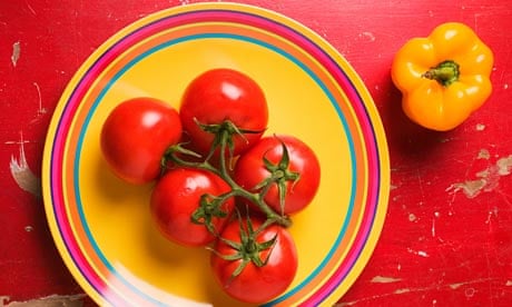 Five tomatoes on plate with yellow bell pepper