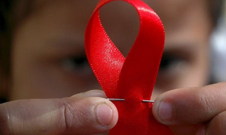 A child holds a red ribbon for World Aids Day