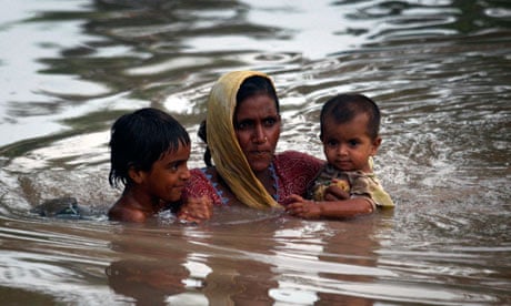 A Pakistani mother carries her children through flood water 