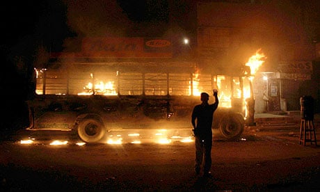 A policeman looks on at a bus torched by political activists in Karachi