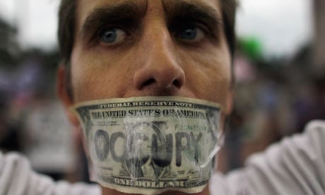 A demonstrator tapes a one dollar bill over his mouth in the Occupy Miami protest