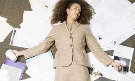 Black businesswoman laying on pile of paperwork
