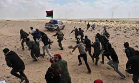 Libyan rebels run for cover after coming under heavy fire near Brega.