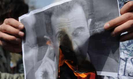 A protestor burns a portrait of Syrian president 