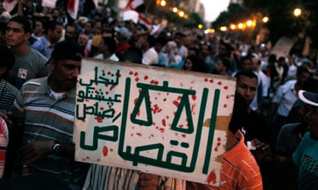 A protester in Tahrir Square carries a placard that reads "Justice or bullets" in Arabic.