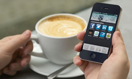Man hand holding an iPhone 4 showing the social networking application screen at a cafe