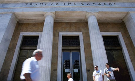 People walk past the headquarters of the Bank of Greece in central Athens