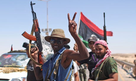 A rebel fighter flashes a victory sign at the gates of the town of Brega, Libya