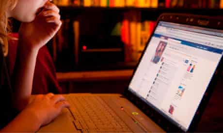 A teenage girl reading her Facebook page on a laptop computer at home, UK