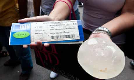 Woman holds her defective PIP breast implant