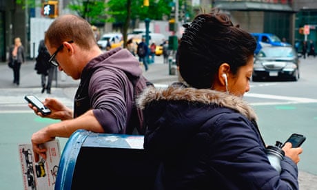 Two people leaning on mail box while using iPhones near Columbus Circle, New York City
