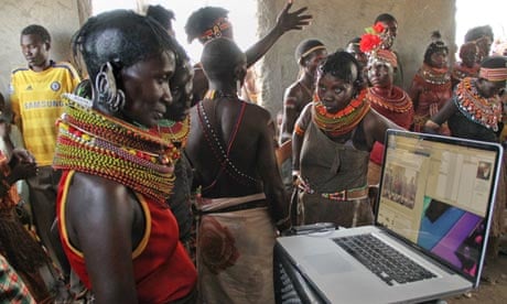 Turkana women examine photos of a festival rehearsal on a laptop in Loiyangaleni, Kenya. 