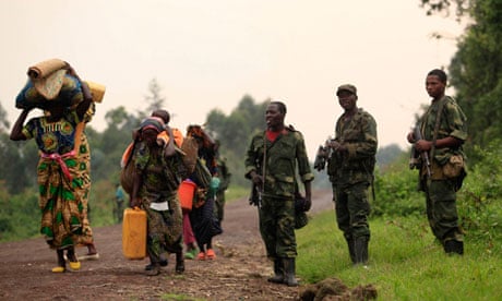 families walk past M23 rebels at Rumangabo