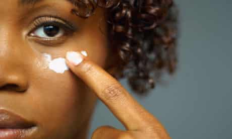 A woman applying cream under her eye