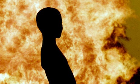 A NIGERIAN CHILD IS SILHOUETTED AGAINST THE GAS FLARE AT UTOROGU SHELL FACILITY IN NIGERIA'S DELTA