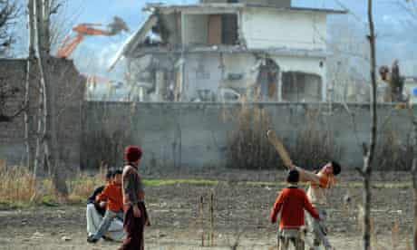 Young boys play cricket beside demolitio