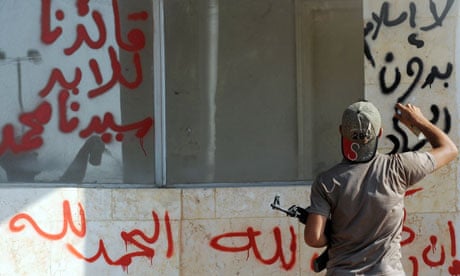 a man sprays an Arabic slogan - No Islam without Jihad - on a wall