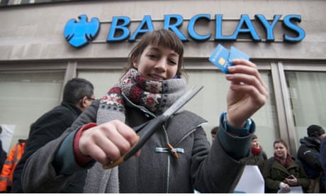 A customer cuts up her bank card outside a London branch of Barclays