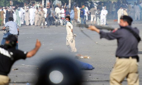 A demonstrator throws stones at police in Karachi.