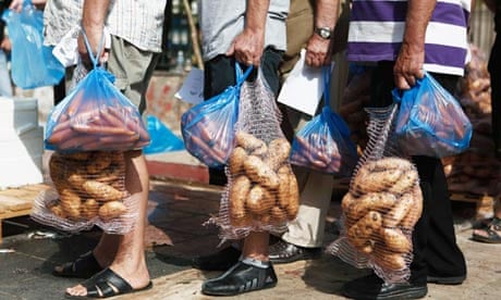 People hold sacks of potatoes during a food distribution organised by Golden Dawn, in Athens.