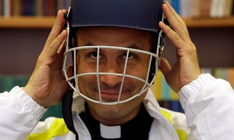 Monsignor Sanchez de Toca, puts on a cricket helmet after unveiling the Vatican team