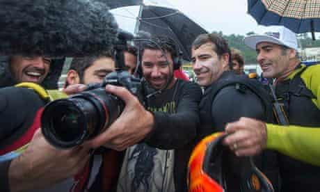 Brazilian surfer Carlos Burle, (2nd r) watches footage of himself suring giant waves in Nazare
