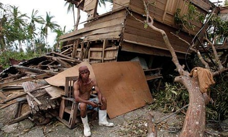 A man takes a break from salvaging reusable woods from his damaged house in Tabogon