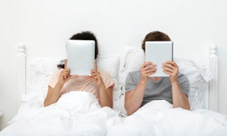 Couple in bed with iPads