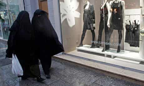 Women wearing niqabs walk past fashion stores on the street in Marseille
